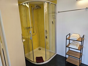 Eine begehbare Dusche mit Glastrennwand, einem Handtuchhalter und einem Ablagebereich mit gefalteten Handtüchern.