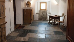 A room with a stone floor, wooden furniture, an arched ceiling, and a window.
