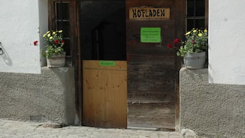 Eine Holztür mit einem Schild, auf dem 'HOTLADEN' steht, und einem grünen Schild mit den Öffnungszeiten.