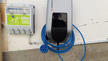 A wall-mounted electric vehicle charging station with a visible plug and a cable connected to it.