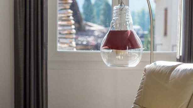 Ein Zimmer mit Fenster, einem Sessel und einer Pendelleuchte.