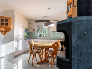 Une cuisine moderne avec un coin repas, comprenant un grand îlot central, des chaises en bois et un four encastré.