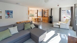 Ein modernes Wohnzimmer mit Sofa, Essbereich, Küche und Kamin.