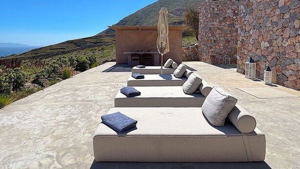 Terraza en la azotea con mobiliario exterior y un muro de piedra.