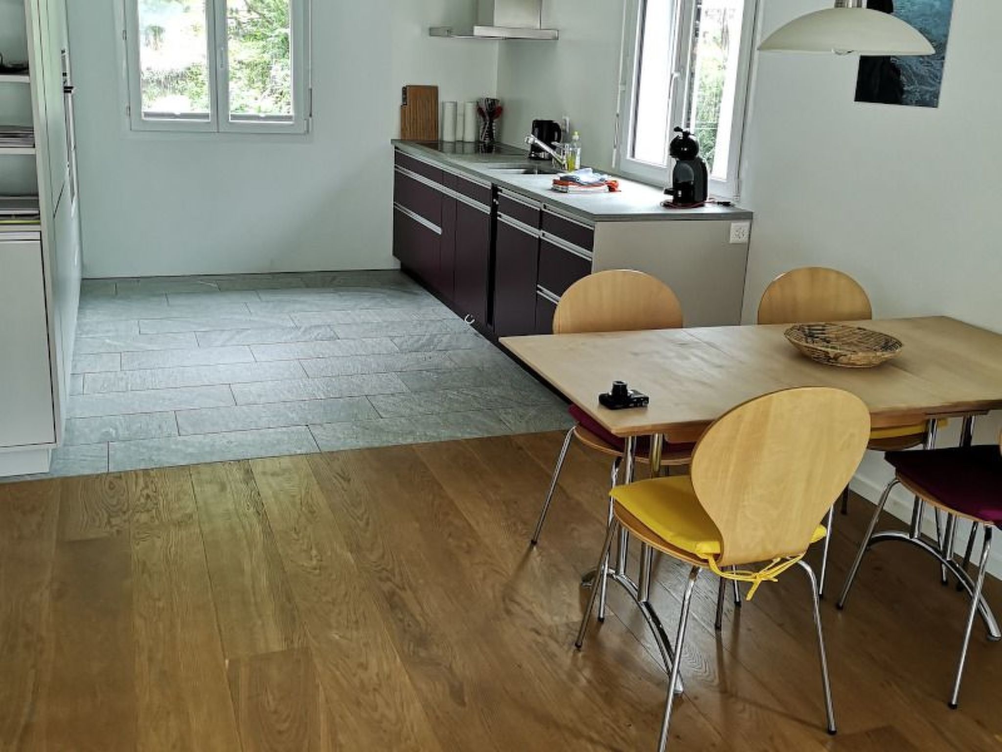 Une cuisine avec un coin repas, un plancher en bois et une fenêtre.