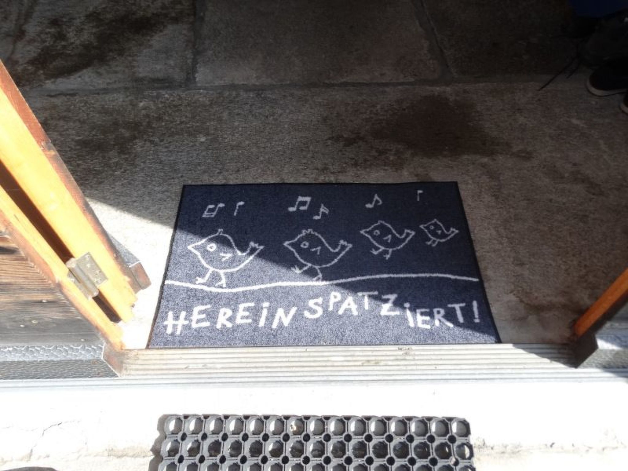 Eine Fußmatte mit Noten und dem Aufdruck 'HEREIN SPATZIERT!'