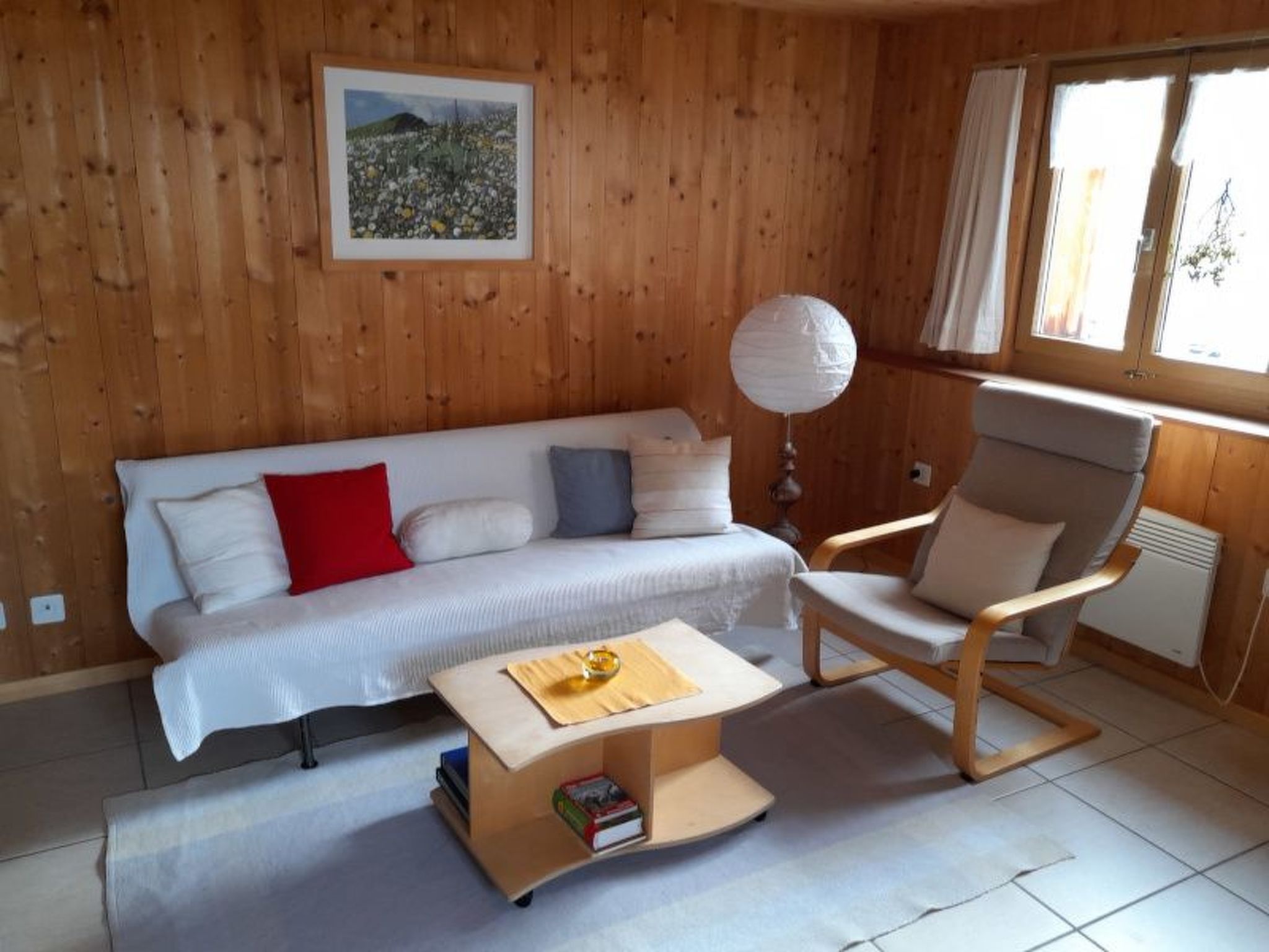 Un interior de madera con un sofá, una silla y una mesa con un libro.