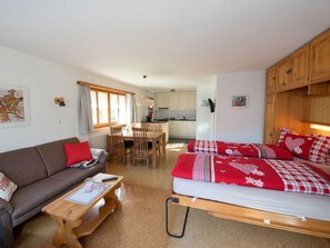 A cozy room with a bed, a sofa, a dining table, and a kitchen area. - Ferienhaus Muntschi, (Andeer), by Interhome (Andeer)