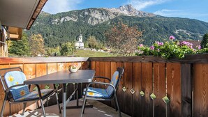 An outdoor patio with a table and chairs, a wooden fence, and a mountain view. - Ferienhaus Muntschi, (Andeer), by Interhome (Andeer)