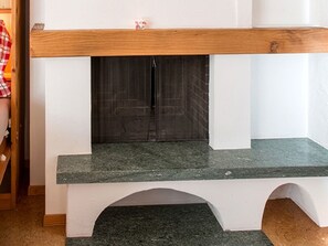 A fireplace with a stone mantle and a wooden mantel above it. - Ferienhaus Muntschi, (Andeer), by Interhome (Andeer)