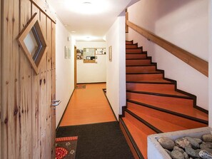 Eine Holztreppe mit Teppichstufen führt zu einem Raum mit Schreibtisch und Spiegel.