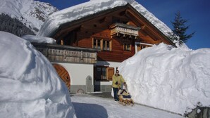 Una cabaña de madera con balcón, rodeada de nieve.