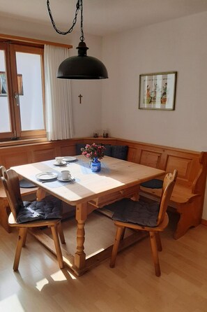 Een eetgedeelte met een houten tafel, stoelen en een bank.