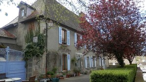 A two-story building with a courtyard, potted plants, and a blue gate. - 3 Place des Arbres (Felletin)