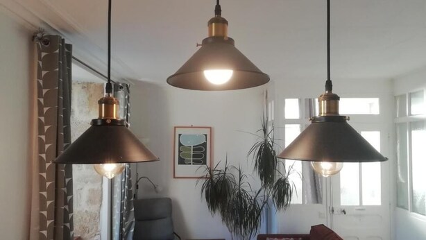 A living room with a sofa, a chair, a small table, and two hanging pendant lights. - 3 Place des Arbres (Felletin)