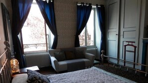 A bedroom with a bed, a sofa, a radiator, a window with curtains, and a wardrobe. - 3 Place des Arbres (Felletin)