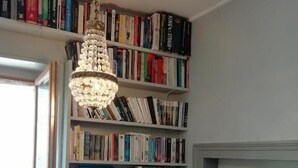 A room with a bookshelf filled with books, a chandelier, and a door. - 3 Place des Arbres (Felletin)