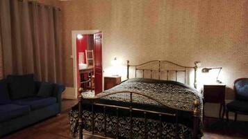 Un dormitorio con una cama, un sofá azul, suelo de madera y una pared con estampado.