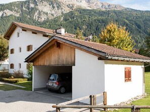 A two-story house with a garage, a car parked inside, and a mountainous backdrop.