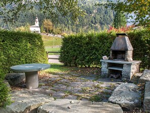 A stone patio with a stone table and an outdoor grill.