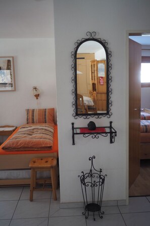 A bedroom with a bed, a bedside table, a mirror, and a small shelf with a decorative item. - Wohnung Sut Baselgia, (Andeer), by Interhome (Andeer)