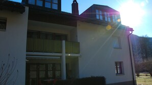 A two-story building with a balcony, a covered outdoor seating area, and a clear sky.