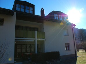 A two-story building with a balcony, a covered outdoor seating area, and a clear sky.