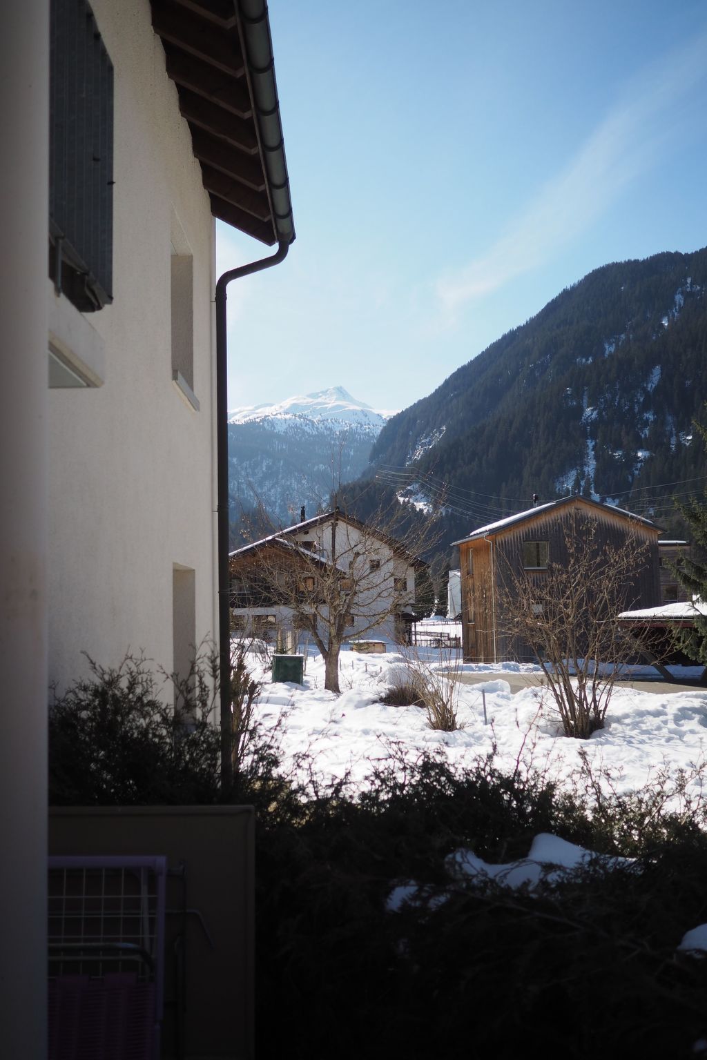 A residential area with houses, a snowy landscape, and mountains in the background.