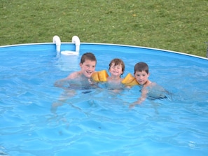 A swimming pool with three children holding yellow floatation devices.