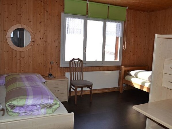 A room with a bed, a chair, a desk, and a window.