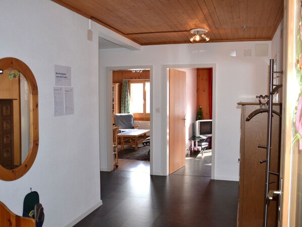 Un pasillo con techo de madera, un espejo y perchero. Hay puertas que dan a otras habitaciones.