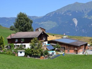 A chalet with a sloped roof, solar panels, and a view of mountains.