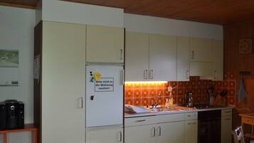 Eine Küche mit weißen Schränken, einem Kühlschrank und einer gefliesten Spritzschutzwand.