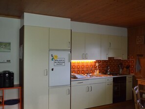 A kitchen with white cabinets, a refrigerator, and a tiled backsplash. - Wohnung Hof Coms, (Urmein), by Interhome (Urmein)