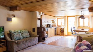 A cozy living room with a sofa, a television, and a fireplace. - Haus Aebli, (Hinterrhein), by Interhome (Hinterrhein)