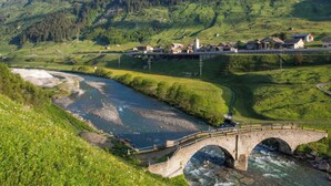 A bridge over a river, surrounded by green hills and a small village with houses and a church. - Haus Aebli, (Hinterrhein), by Interhome (Hinterrhein)
