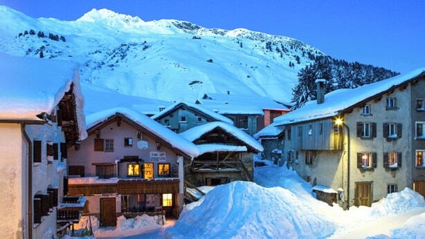 A snow-covered village with traditional buildings, a ski lift, and a mountain backdrop. - Haus Aebli, (Hinterrhein), by Interhome (Hinterrhein)