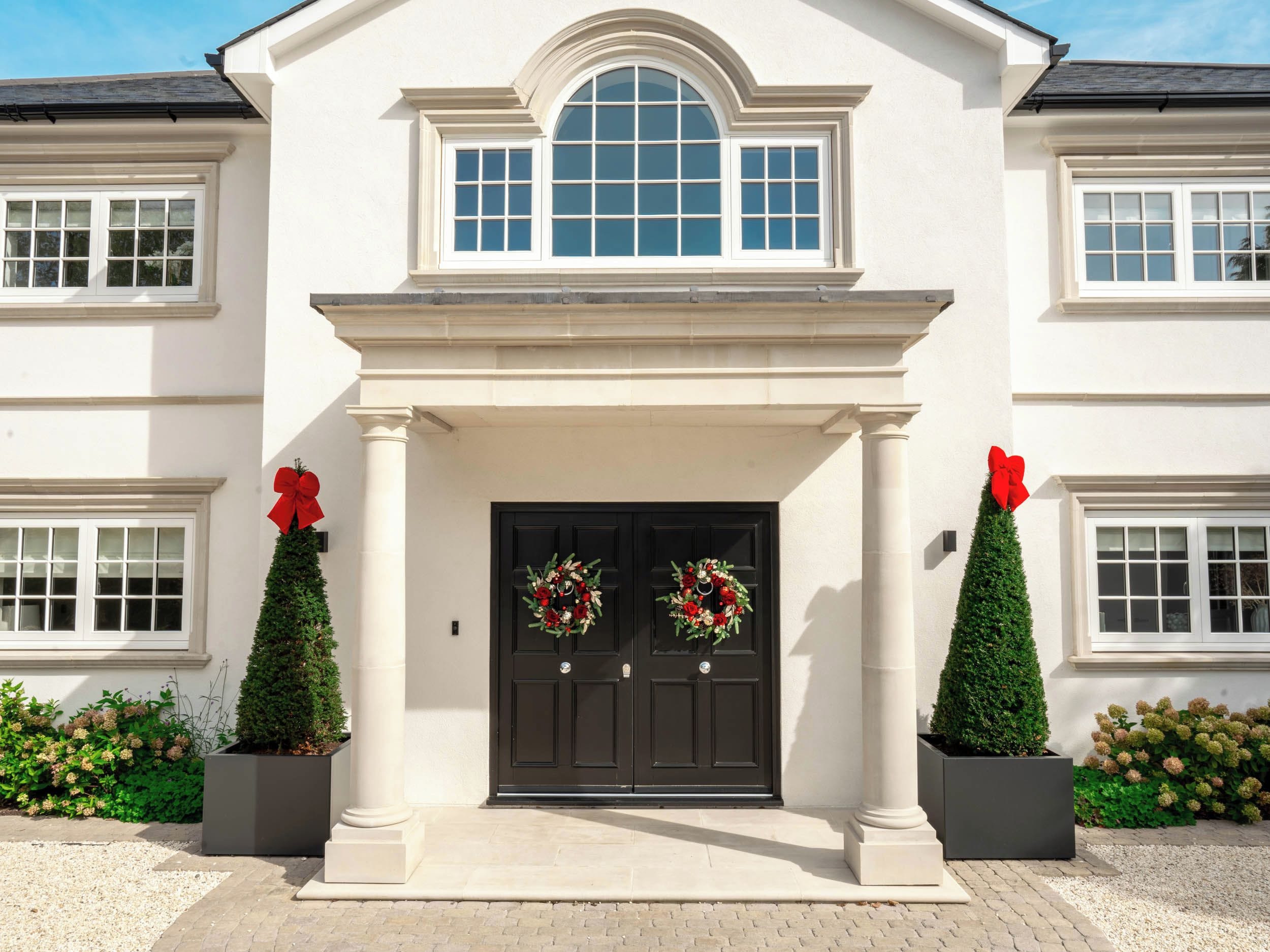 A two-story building with a central entrance, flanked by two columns, and a large arched window above the door.
