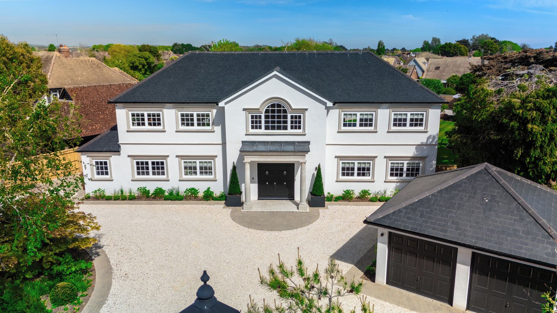 A large, two-story house with a symmetrical facade, a central entrance, and a driveway leading to a garage.