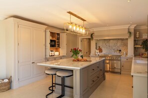 A spacious kitchen with a large island, built-in appliances, and a modern pendant light. - Sea Estate House (Littlehampton)