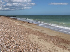 A pebbled beach with a wooden jetty extending into the sea. - Sea Estate House (Littlehampton)