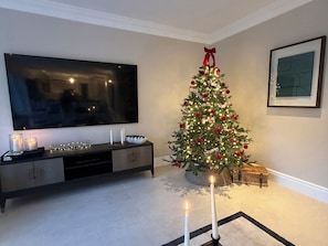 Uma sala de estar com televisão, árvore de Natal e lareira.