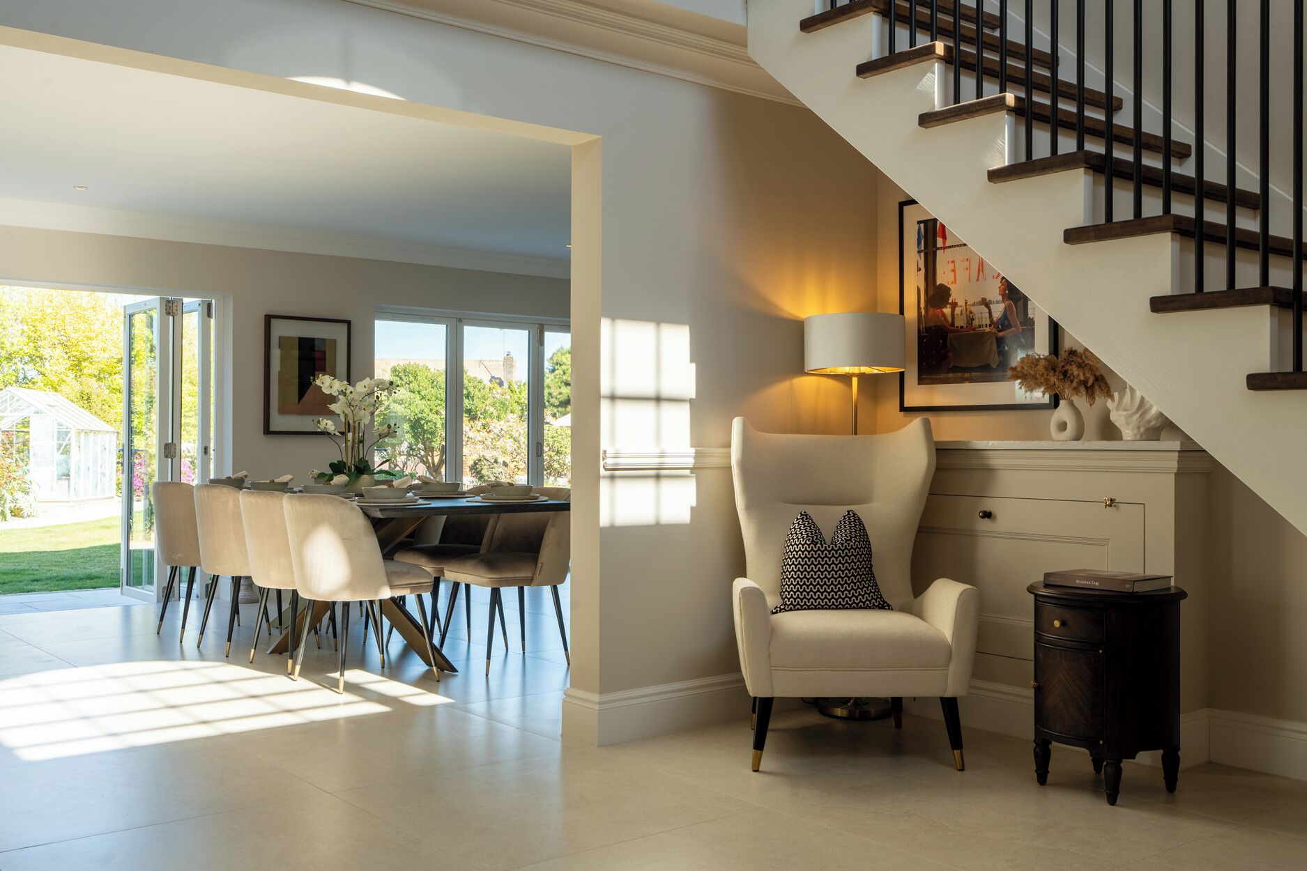 Un interior moderno con zona de comedor, escalera y vistas al exterior.