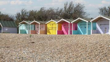 Uma fileira de cabanas coloridas à beira de uma praia de pedras.