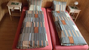 Two single beds with striped bedding, wooden nightstands with lamps, and a wooden floor.