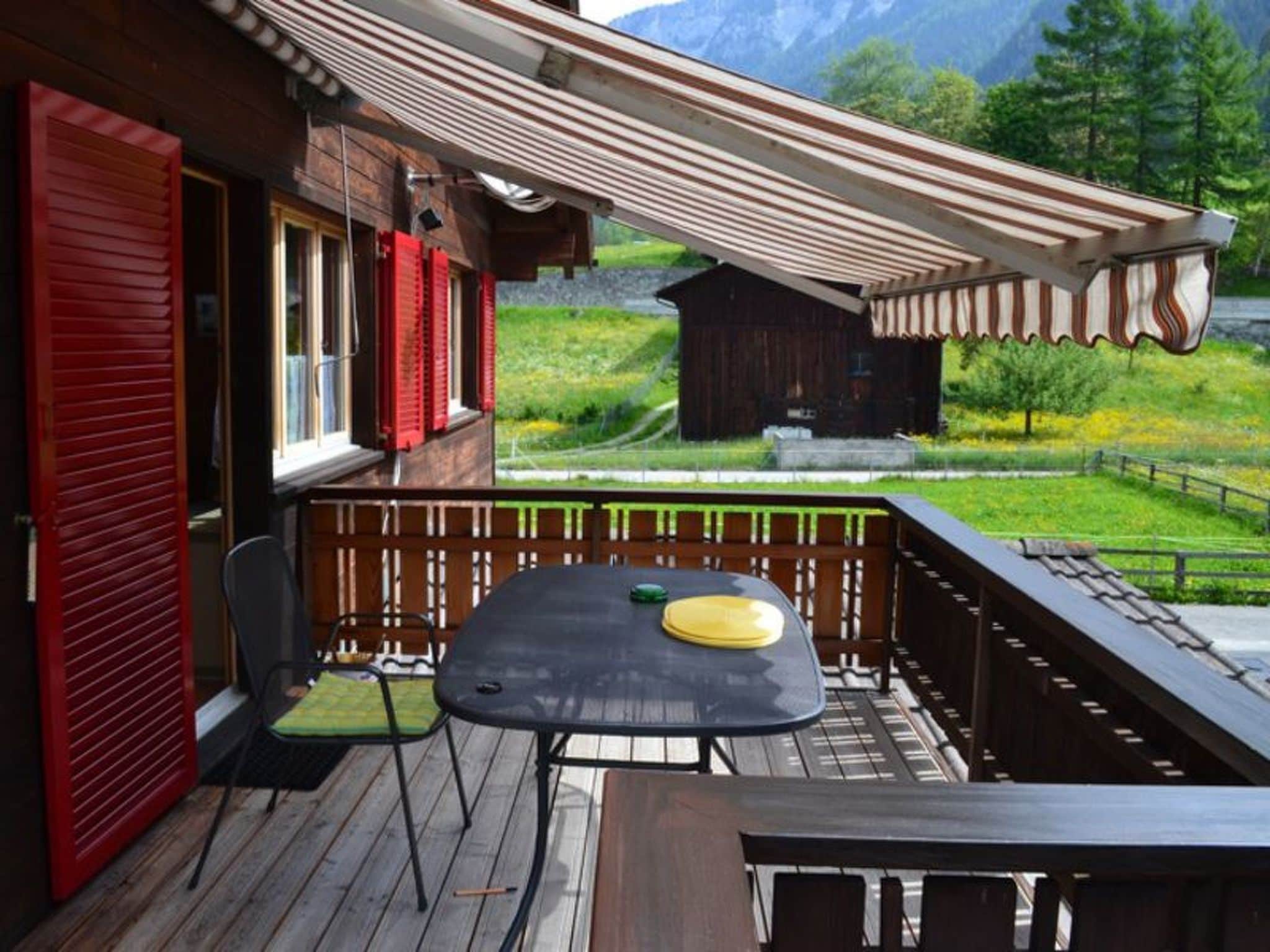 Un terrazzo in legno con tavolo e sedie, affacciato su un paesaggio montuoso.