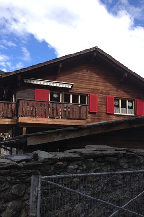 A wooden chalet with a balcony, red shutters, and a stone foundation. - Tgea Sulagliva, (Andeer), by Interhome (Andeer)