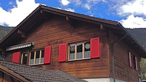 A wooden chalet with red shutters, a sloped roof, and a view of the mountains. - Tgea Sulagliva, (Andeer), by Interhome (Andeer)