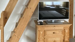 Ein Fernseher auf einer Holzkassette in einem Raum mit sichtbaren Holzbalken.