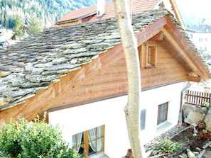 A traditional chalet with a sloped roof, wooden beams, and a window with curtains. - Haus Fravgia veglia, (Andeer), by Interhome (Andeer)